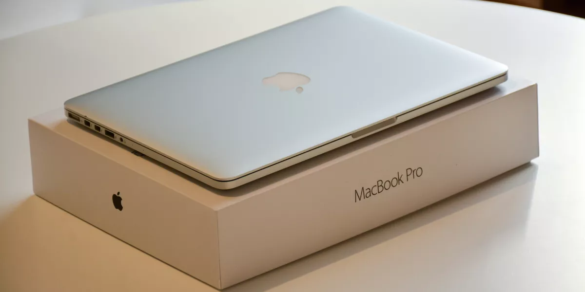 Silver MacBook Pro on its packaging box with the Apple logo visible.